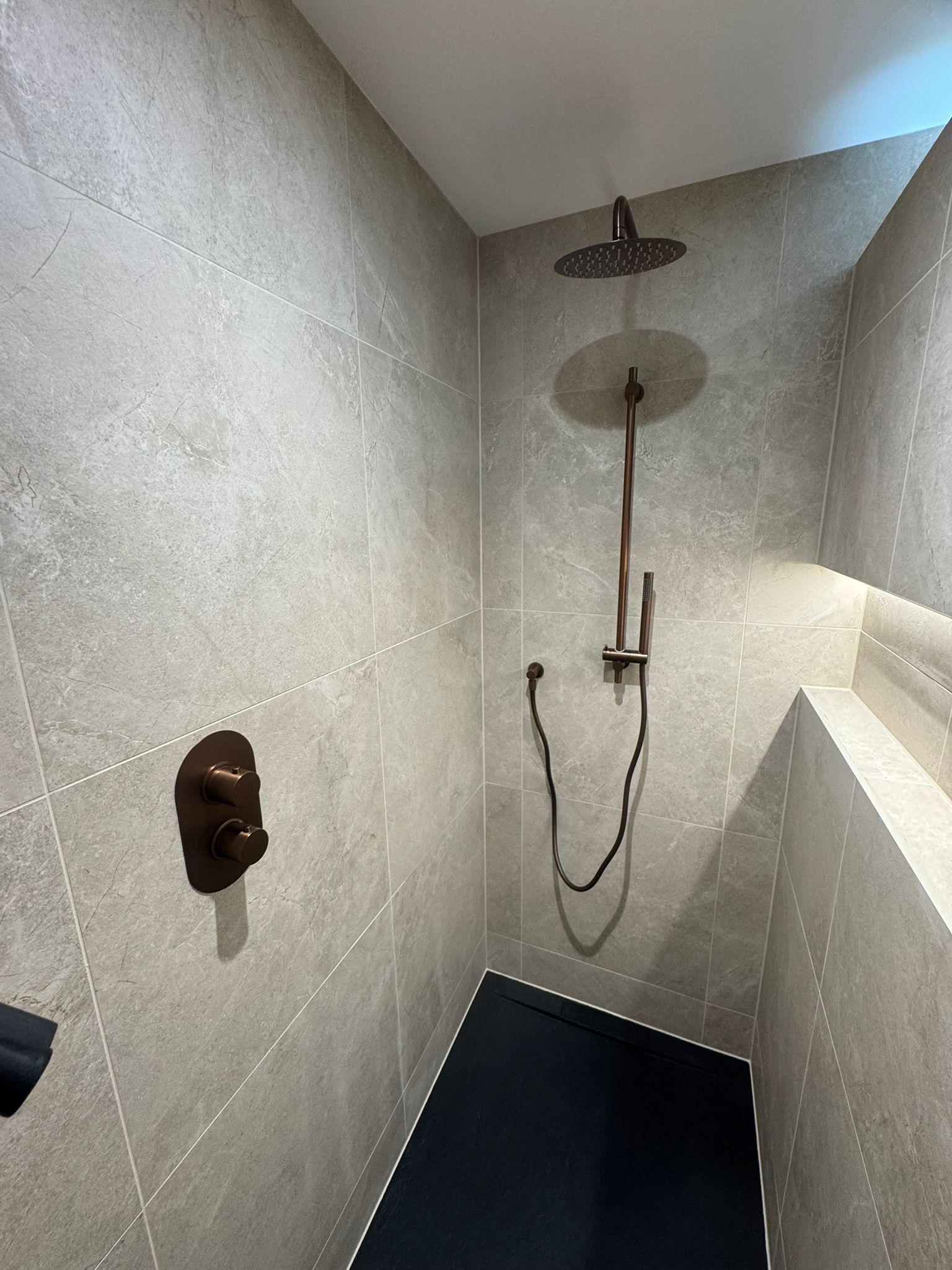 Stone walk-in shower with bronze fittings